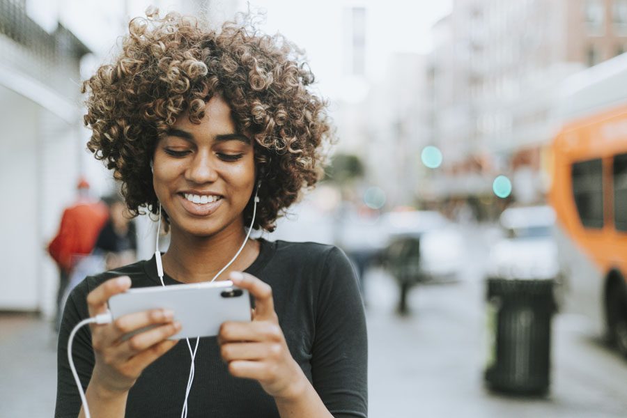 Video Library - Woman Listening to a Video Through Headphones on the Way to Work in the City